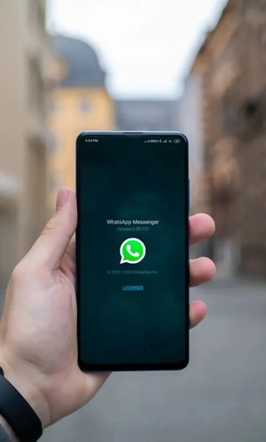 Hand holding a smartphone displaying the WhatsApp logo, representing mobile-first chat automation and marketing services.