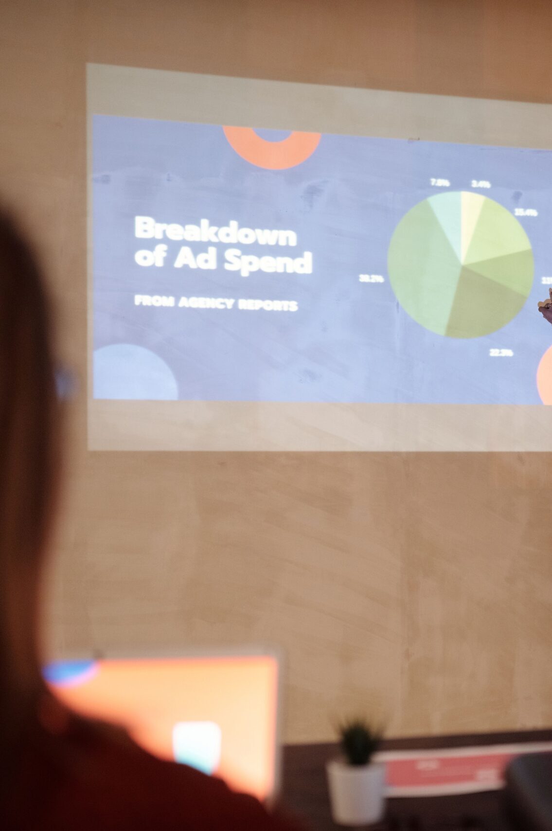 Young man delivering a business presentation on ad spend with charts and graphs in a modern office setting.