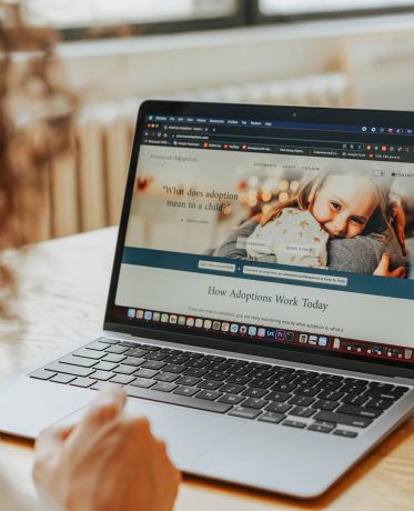 A woman researching adoption information on a laptop indoors.
